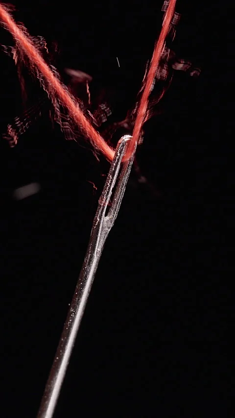 Vertical video. Fingers Thread Red Thread Through a Sewing Needle Against Black, Stockbeeldmateriaal 341416603
