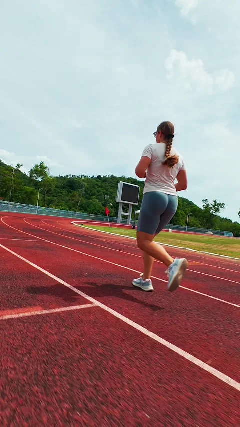Vertical video. First Person FPV Drone Chasing a Woman Running Around a Stadium Stock Footage 338188673