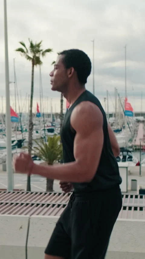Vertical video, Fit Black Man Runs by the Marina Stock Footage 313553040