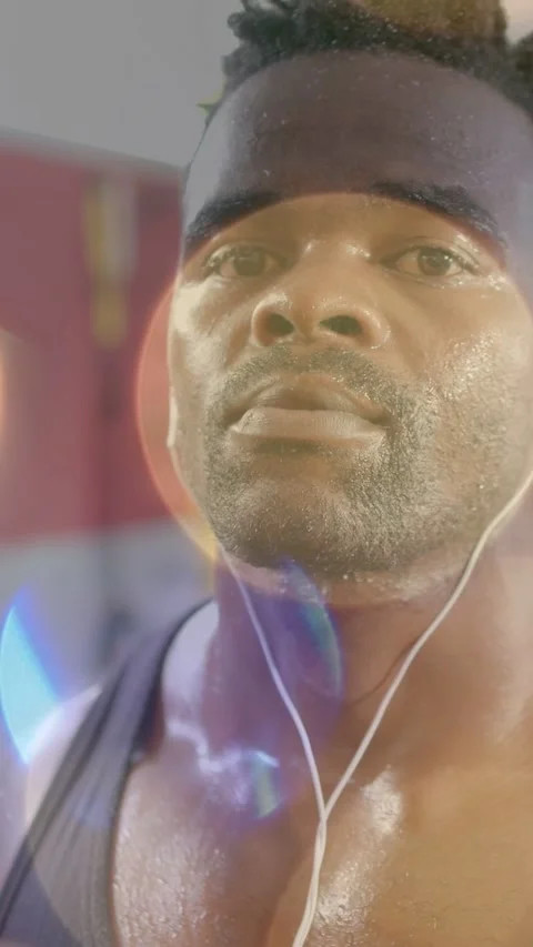 Vertical video: Fit man cooling in fitness gym as camera panning up, earphones Stock Footage 333658287