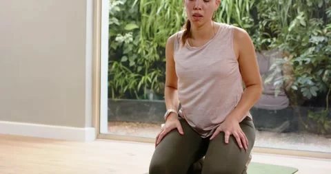Vertical video: Fixing shoe pink top woman kneeling on mat rolling shoulders Stock Footage 341468403