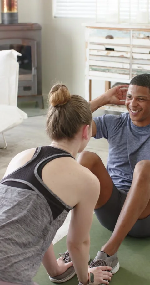 Vertical video: Flexing abs muscles, man is doing sit-ups on mat with partner Stock Footage 345395830