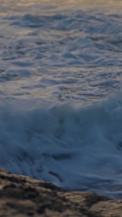 Vertical video of Foaming ocean waves crashing on rocky shore at dusk Stock-Footage 330470991