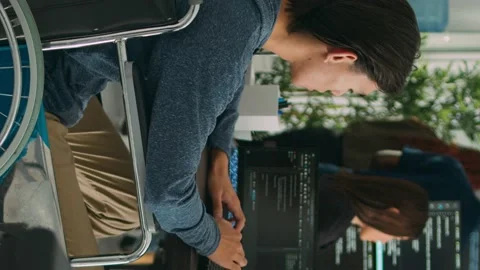Vertical video: Focused software developer in wheelchair writing server code in Stock Footage 219702082