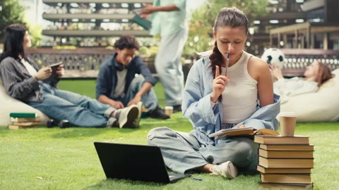 Vertical Video Focused student writing in notebook beside open book Stock Footage 340795787