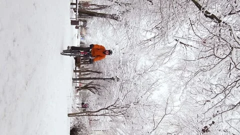 Vertical video footage of a guy rides a bicycle through a winter city Stock Footage 262610448