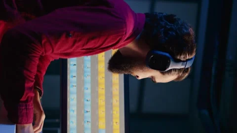 Vertical video Freelancer using photographs retouching program, hearing songs Stock Footage 258802967