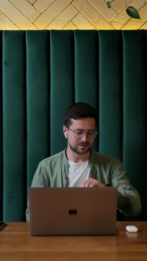 Vertical video. Friendly guy video chatting at cafe with headphones. Stock Footage 345236406