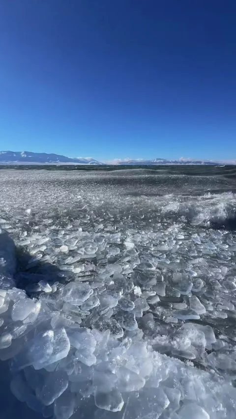 Vertical video of frozen ice waves rolling and crashing on shore of Sayram L Stock Footage 327691900