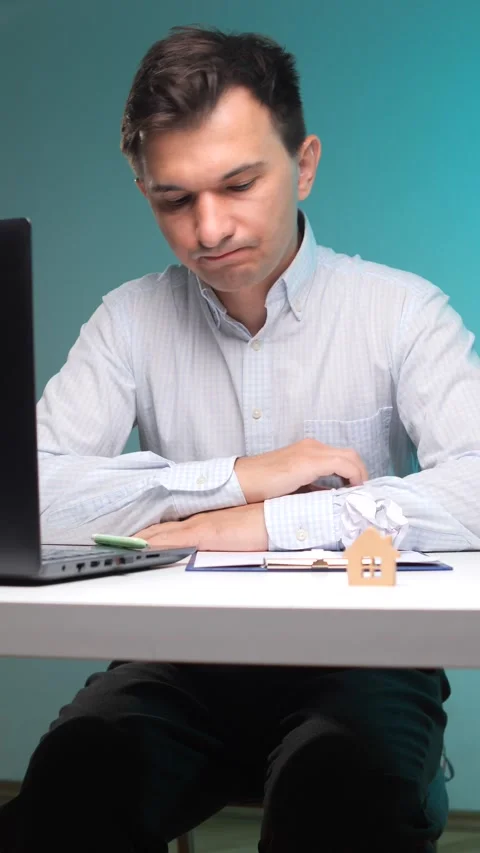Vertical video frustrated man crumpling a document at his desk with a laptop Stock Footage 342762499