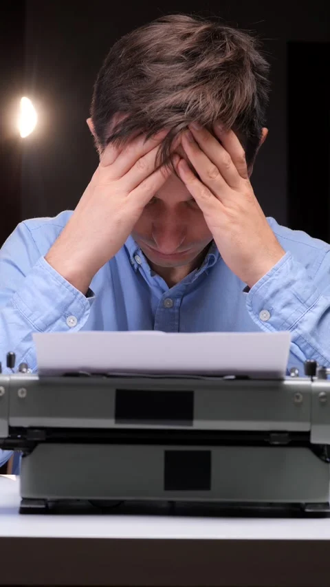 Vertical video Frustrated man sitting at his desk, holding his head in hands Stockbeeldmateriaal 321621380