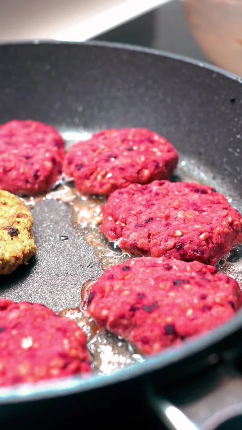 Vertical video of Frying Beetroot and Quinoa Vegan Burger Patties in a Pan Stock Footage 332643279