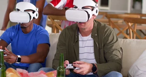 Vertical video: Game starting two men in white VR headsets on sofa using Stock Footage 341938450