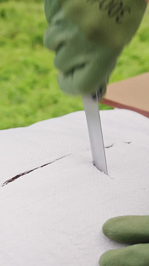 Vertical video. Gardener Wearing Protective Gloves Cuts Open a White Soil Bag wi Stock Footage 340248799