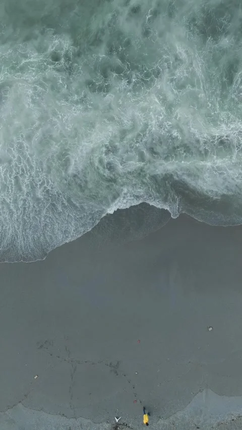 Vertical Video of Gentle Rolling Waves Under Coastal Pier With Sun Umbrellas and Stock Footage 342303409
