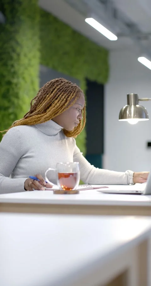 Vertical video: Glancing African American woman using laptop pulling page Stock Footage 342035898