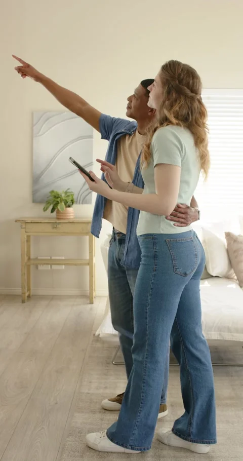 Vertical video: Glancing at tablet, couple pointing at painting while planning Stock Footage 345395850