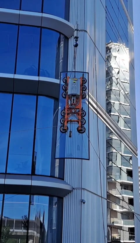 Vertical video of glass panel hoisted past high-rise first level Stock Footage 337359363