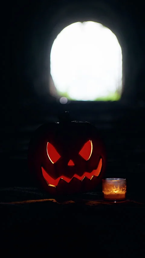 Vertical video. Glowing Jack O Lantern And Candle Inside Dark Tunnel With Bright Stock Footage 337105906