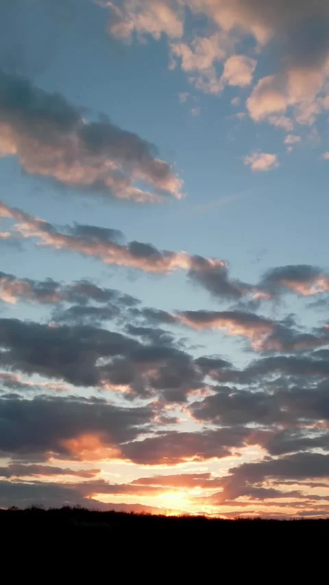 Vertical video. Golden sun setting behind a hill with cloudy sky Video stock 334804996