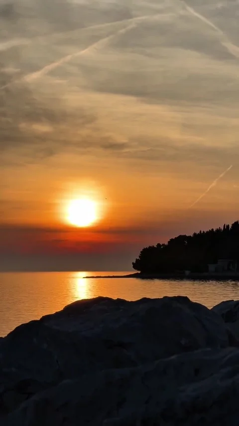 Vertical Video of Golden Sunset Over Calm Sea with Rocks in Foreground Stock-Footage 337716890