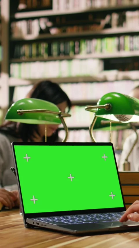 Vertical Video Green screen mockup on laptop with peers at wooden library desk Stock Footage 336379785