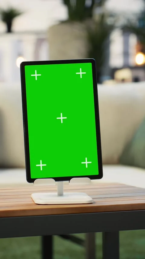Vertical video Green screen tablet on wooden table with plants in background Stock Footage 345166257