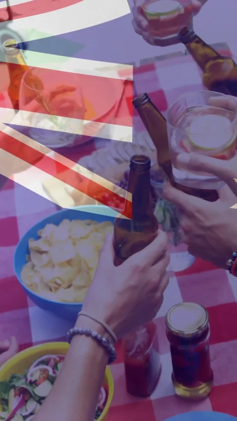 Vertical video: Group clinking drinks as hand lifting beer over food with flag Vídeos de archivo 346122319