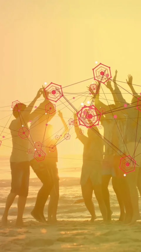 Vertical video: Group raising arms on sunset beach, sparking red hexes linking Stock Footage 334297143