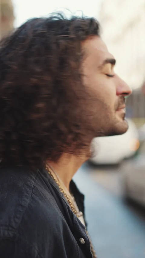 VERTICAL VIDEO: Guy with long curly hair and stubble puts on sunglasses Video stock 226949094
