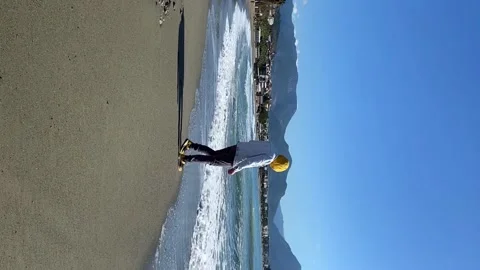 Vertical video. The guy on the seashore plays with the wave Stock Footage 157586821