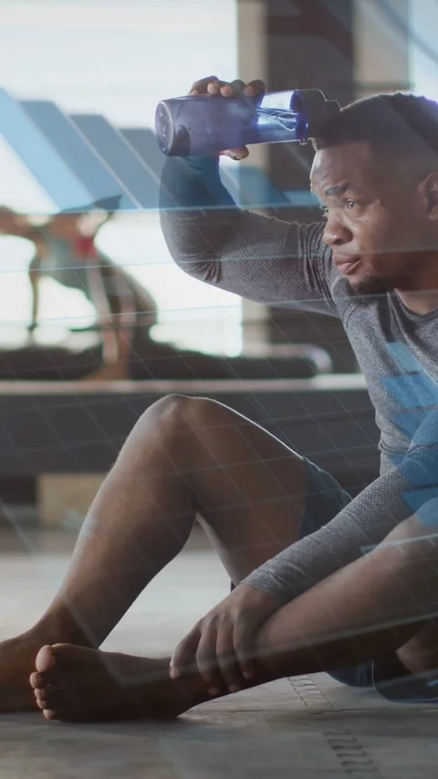 Vertical video: Gym man reaching bottle, dousing head to rest as blue overlays Stock Footage 335513430