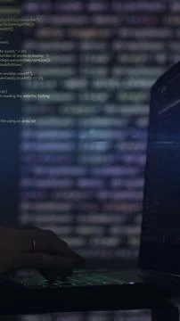 Vertical video. Hacker writing code cracking computer. Programming code in the Фото
