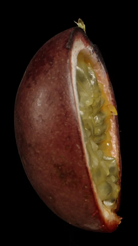 Vertical video. A half of a passion fruit rotates on a black background, showcas Stock Footage 248177476