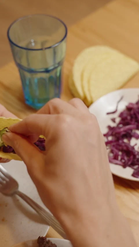 Vertical video. A Hand Adds Fresh Avocado Slices to a Taco Filled with Corn and Video stock 280514594