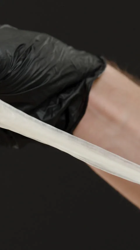 Vertical video. A Hand in Black Gloves Holding and Stretching a Used Condom, Stock Footage 301068127