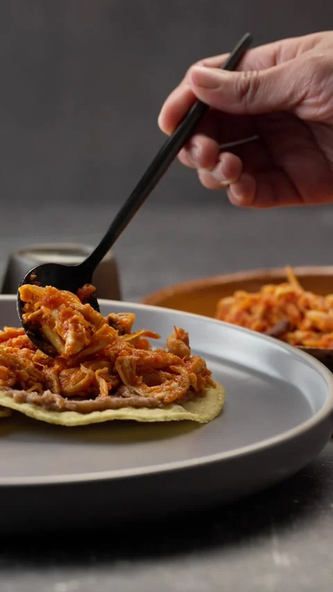 Vertical video, the hand of a dark skinned Mexican woman spreading chicken tinga Stock Footage 282549258