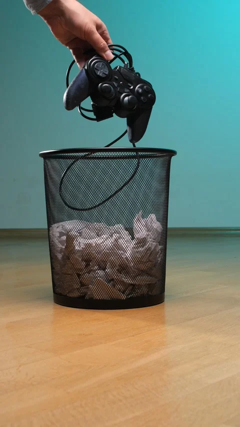 Vertical video hand dropping a black wired video game controller into a metal Stock Footage 342767028