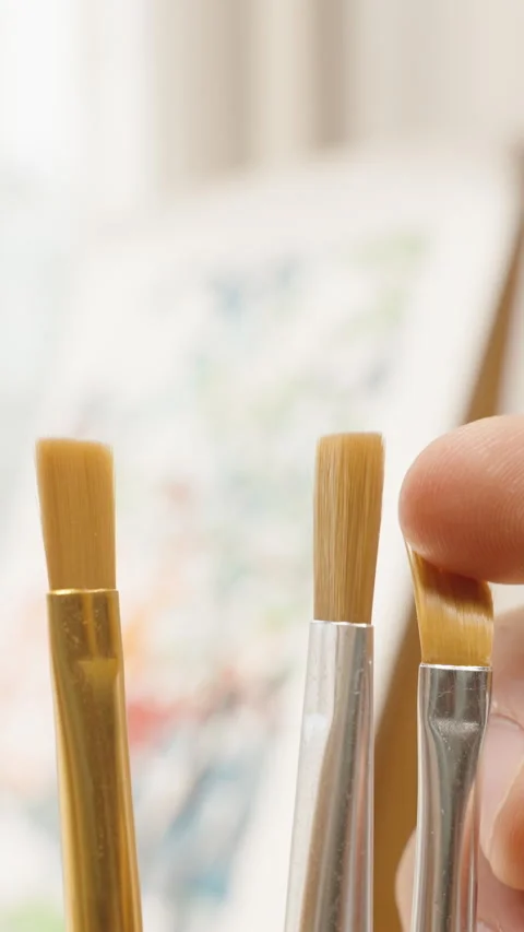 Vertical video. Hand Holding Five Different Small Paintbrushes in Front of Stock Footage 306453367