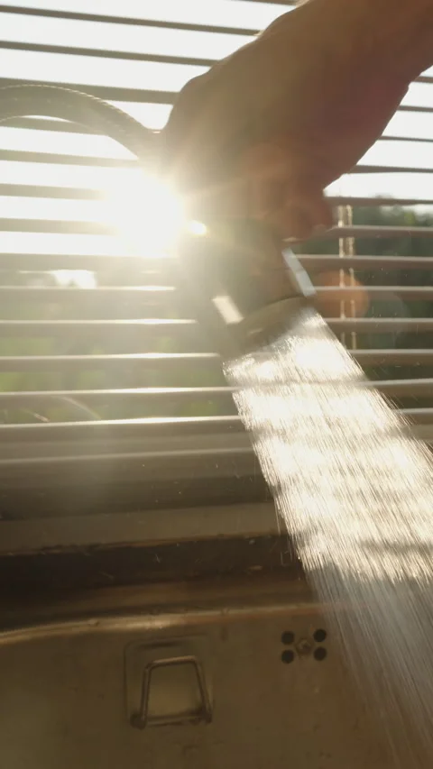 Vertical video. Hand Holding Flexible Faucet Spraying Water into Sink with Stock Footage 308454364