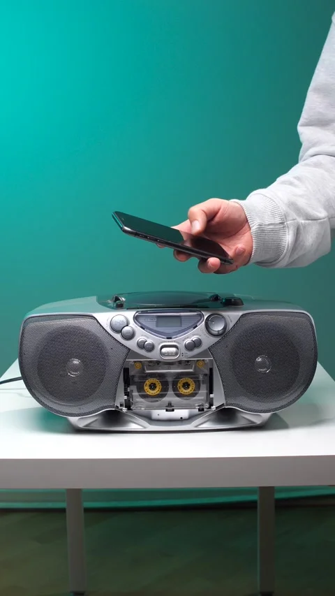 Vertical video hand holding a modern smartphone over a retro cassette player Stock Footage 345530055