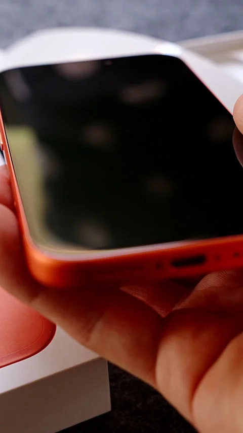 Vertical video. Hand Holding Orange iPhone 17 Pro Above Box with Focus on Dual Vídeo Stock 317696252