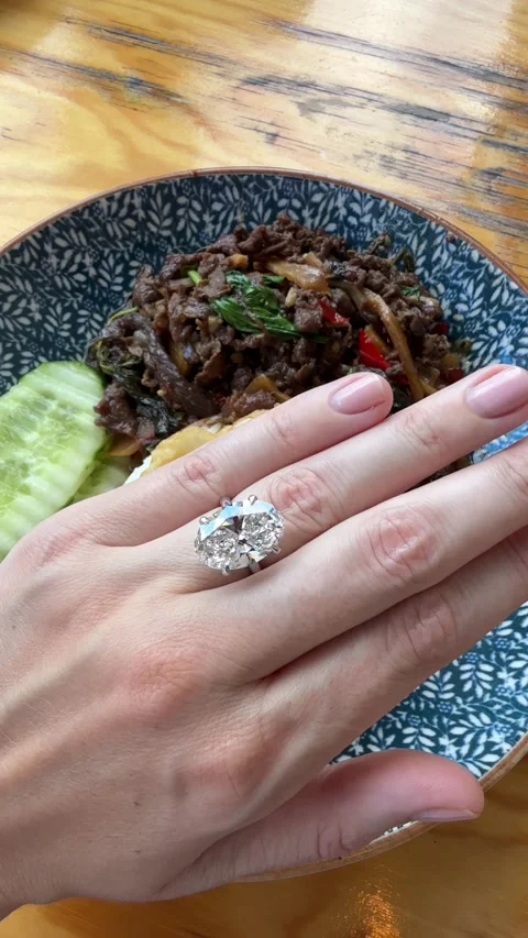 Vertical video of hand with oval diamond engagement ring holding glass Stock Footage 317336832