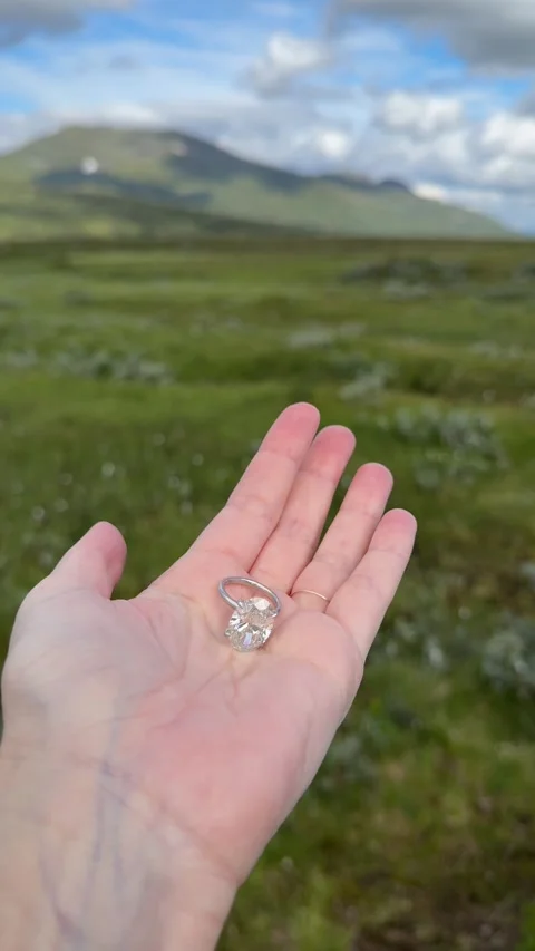 Vertical video hand with oval diamond engagement ring by green slope Stock Footage 317337533