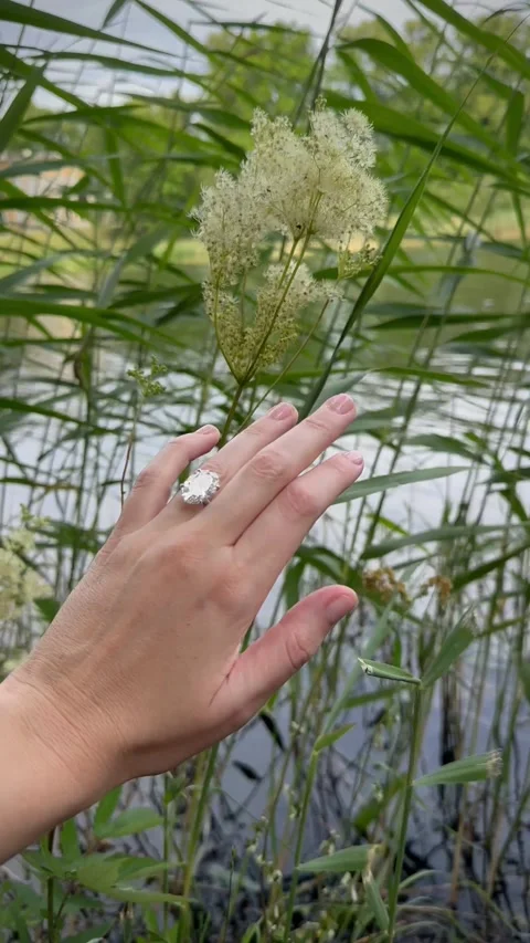 Vertical video hand with oval diamond engagement ring by lake edge Stock Footage 317337542