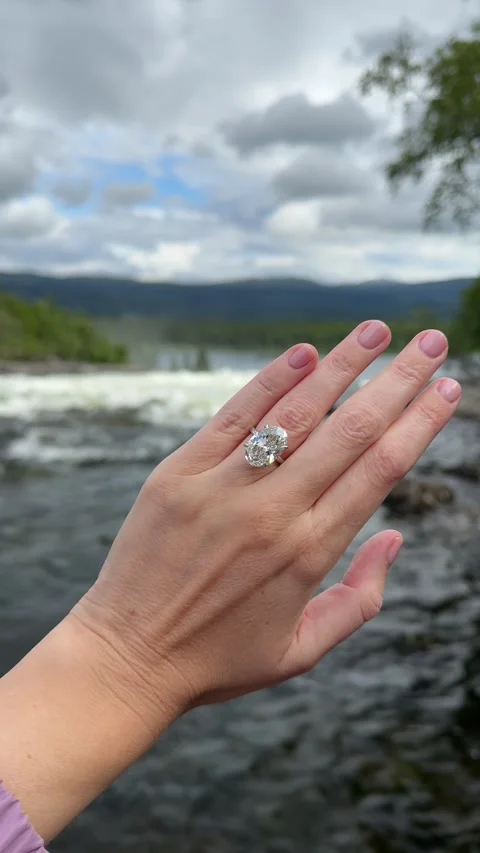 Vertical video of hand with oval diamond engagement ring at river edge 스톡 동영상 317728167
