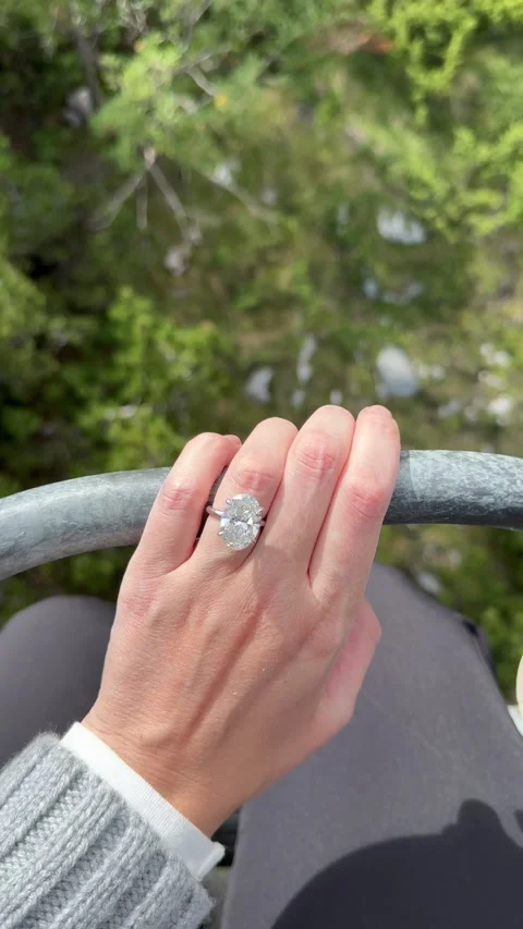 Vertical video of hand with oval diamond engagement ring against green landscape Video stock 319442117