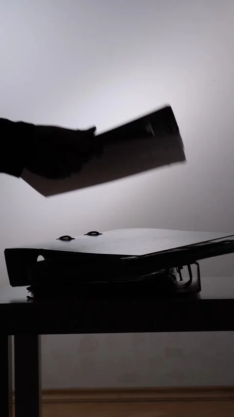Vertical video hand placing a ring binder with documents on a stack of other Stock Footage 347323262