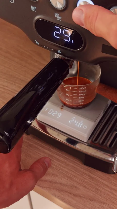 Vertical video. Hand Presses Brew Button On Espresso Machine As Coffee Flows Int Stock Footage 328854467