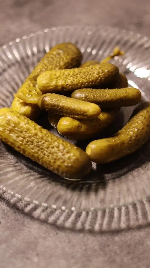Vertical video. Hand puts plate of pickled cucumbers on gray kitchen table Stock Footage 331543923